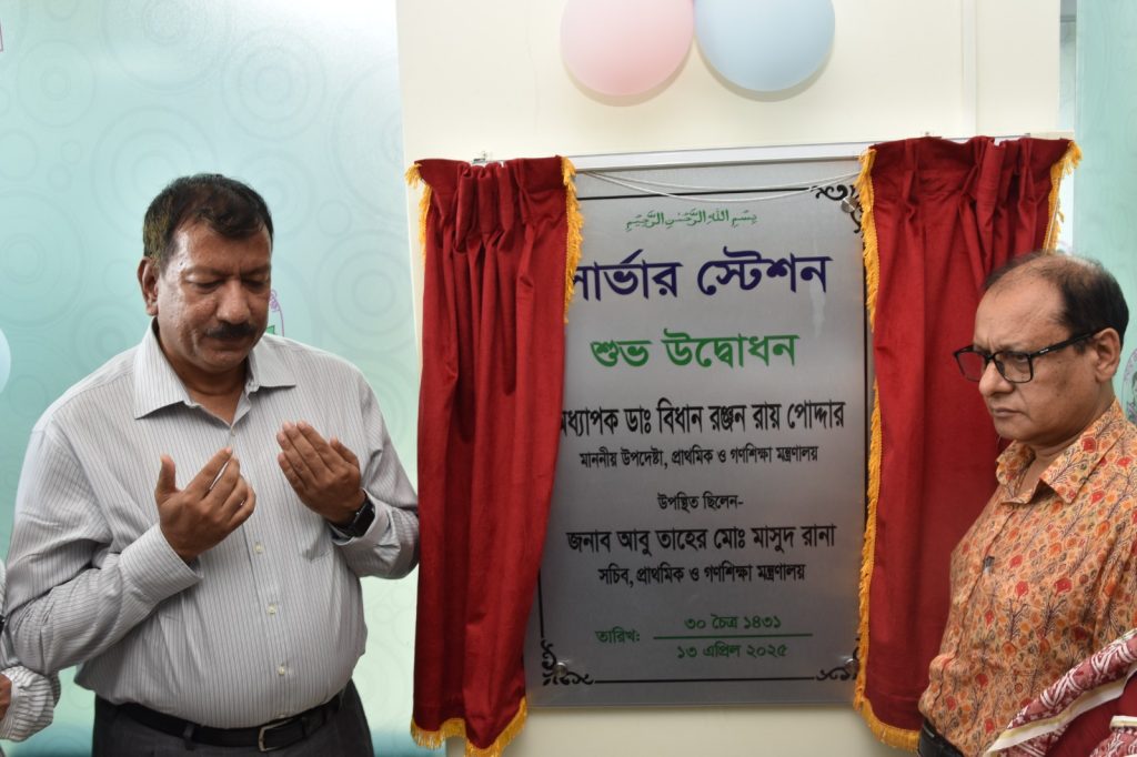 বাংলাদেশে প্রাথমিক ও গণশিক্ষা মন্ত্রণালয়ের সার্ভার স্টেশন উদ্বোধন অনুষ্ঠানে দুই কর্মকর্তা; একজন দোয়া করছেন এবং অন্যজন উদ্বোধনী ফলকের পাশে দাঁড়িয়ে আছেন।